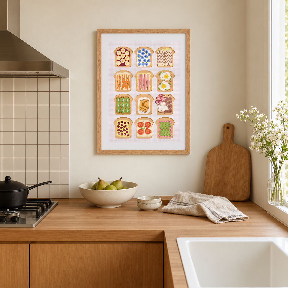 Framed cross stitch pattern of various bread slices with different toppings on a kitchen counter.